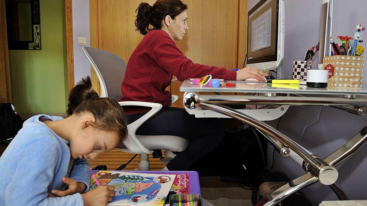 Una empleada trabaja con el ordenador desde su casa junto a su hija.
