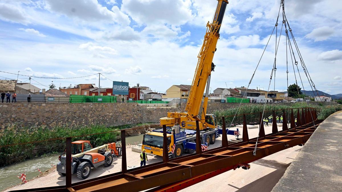 Una grúa levanta una cercha metálica en el lecho del río junto al puente de El Raal.