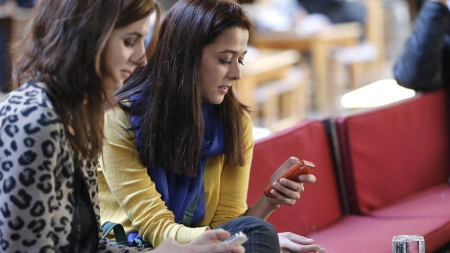 Dos chicas chatean con su móvil.