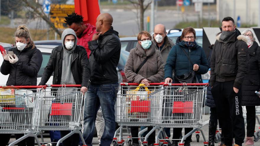 Gent fent cua amb mascaretes en un supermercat