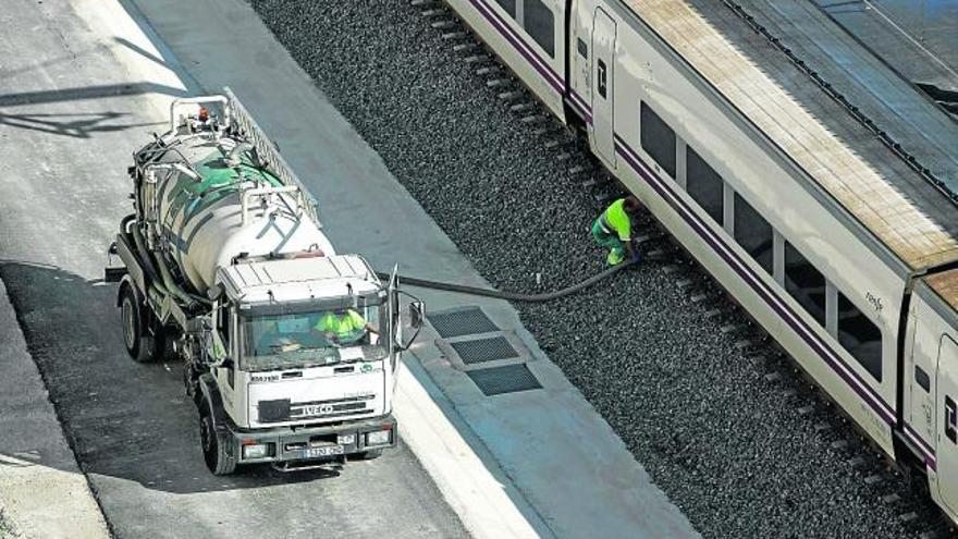 Operarios atendiendo un AVE en la estación de Alicante, ayer, junto a los pisos de la calle Bono Guarner.