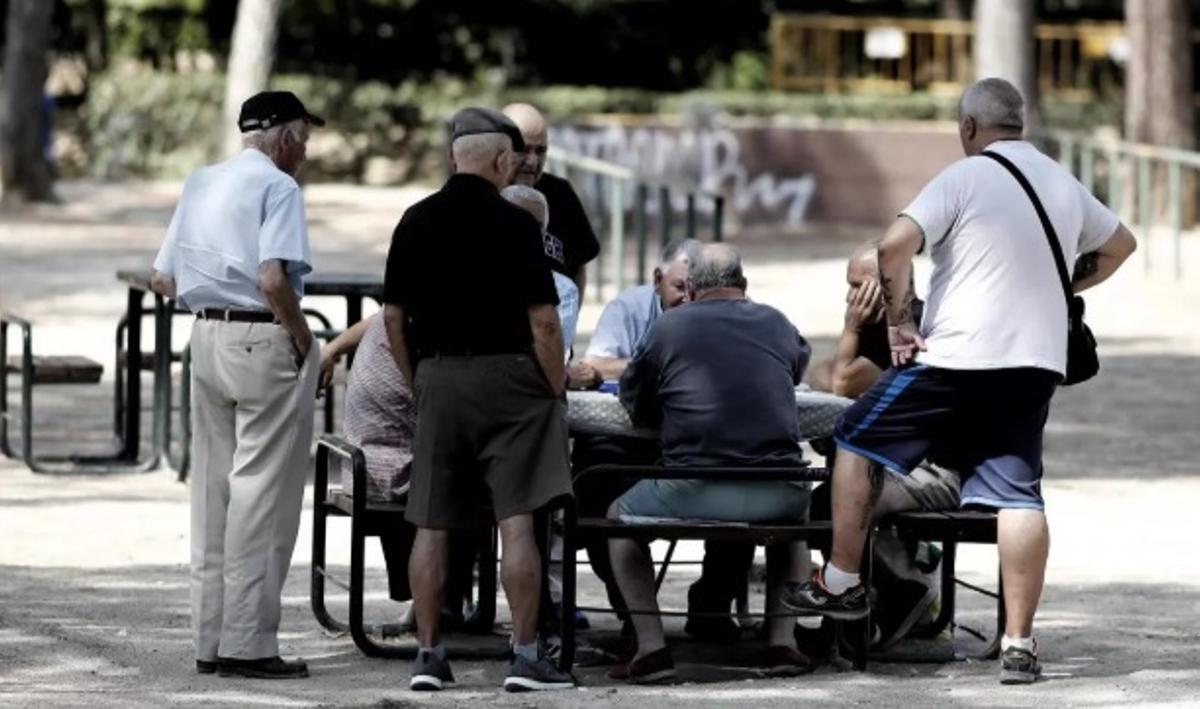 Pensionistas juegan al dominó en un parque.