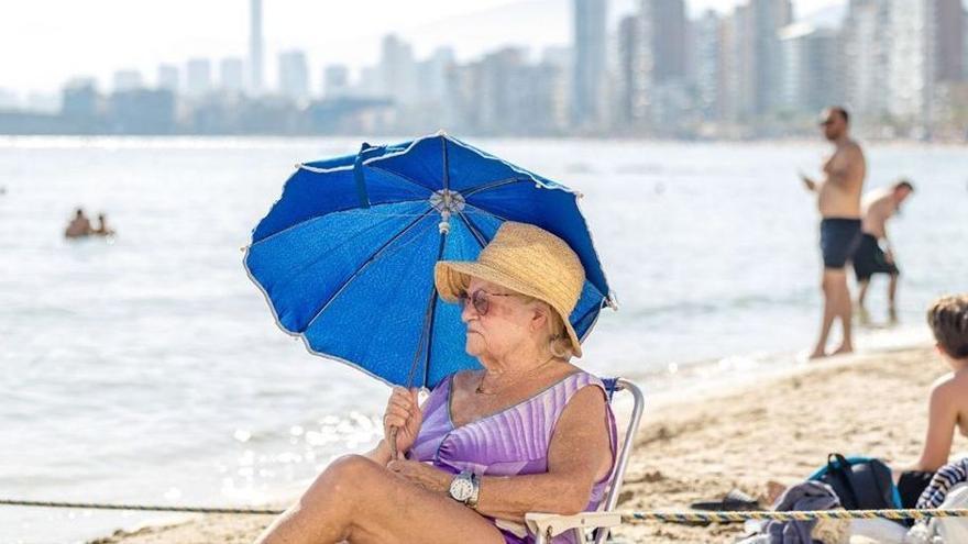 Una señora se protege del sol con una sombrilla en la playa de Levante de Benidorm. / DAVID REVENGA