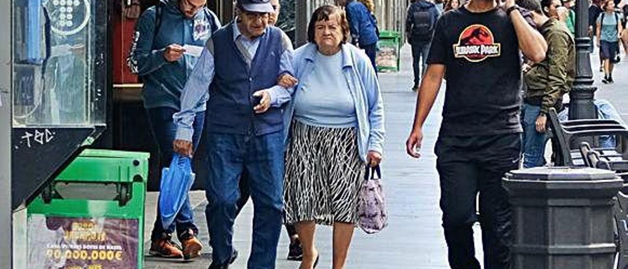 Dos personas mayores pasean por la calle Mayor de Triana.