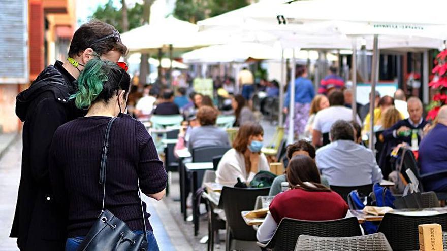 Una pareja espera, con las mascarillas puestas, a ocupar una  mesa en una cafetería abarrotada de la capital. 