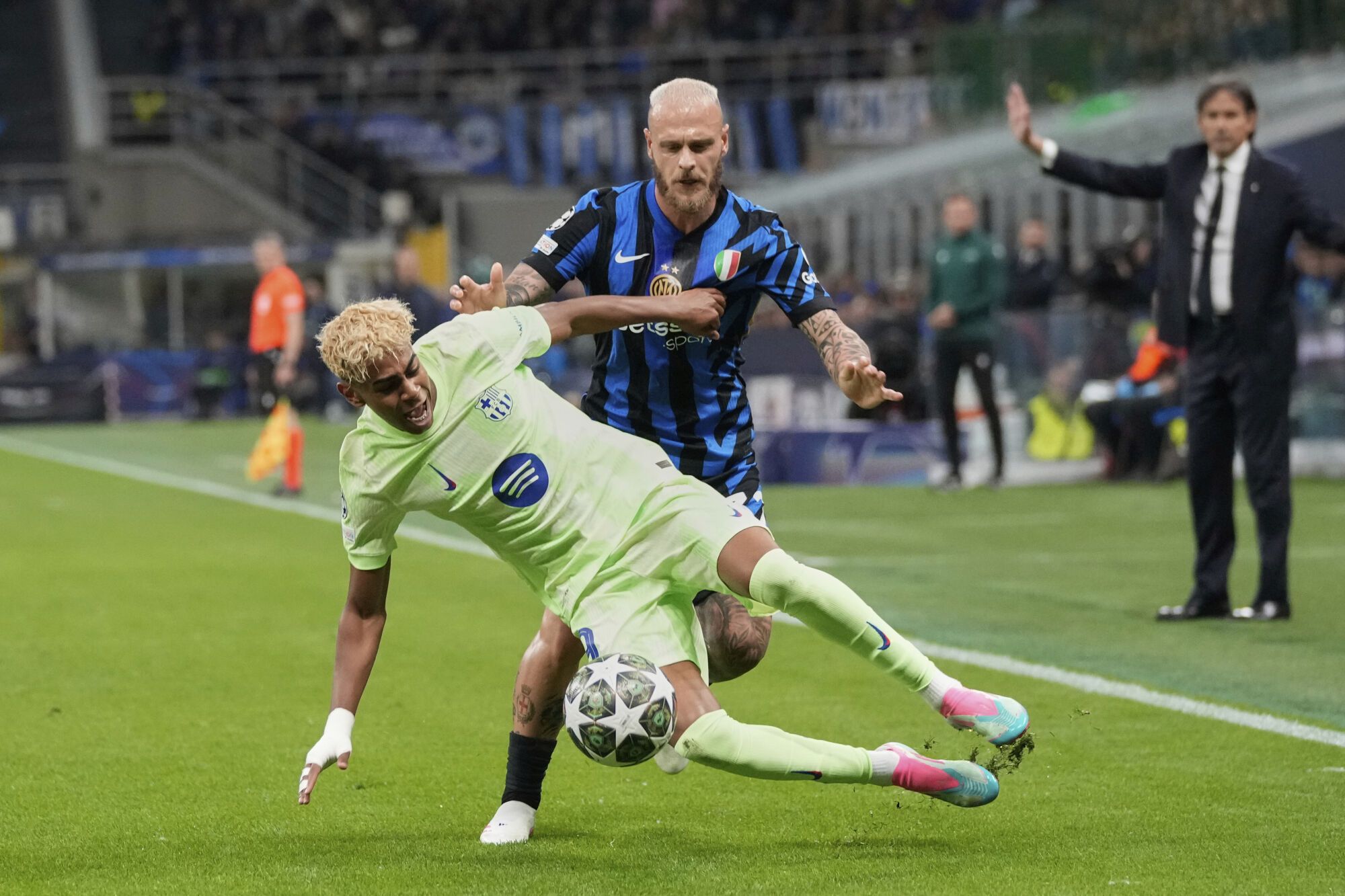 Barcelona's Lamine Yamal, foreground, is challenged by Inter Milan's Federico Dimarco during the Champions League semifinal second leg soccer match between Inter Milan and Barcelona at San Siro stadium in Milan , Italy, Tuesday, May 6, 2025. (AP Photo/Luca Bruno). EDITORIAL USE ONLY / ONLY ITALY AND SPAIN