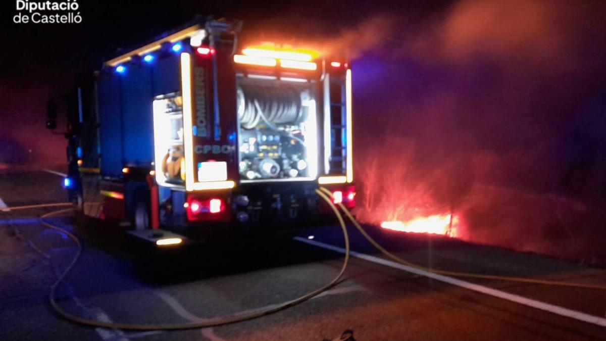 Los bomberos trabajan de madrugada en el incendio del camión accidentado en Alcalà de Xivert.