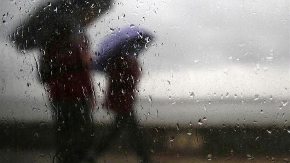 Dos personas se guarecen de la lluvia bajo los paraguas.