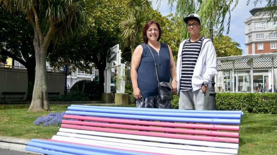 Pablo posa junto a su madre Rosa tras uno de los bancos de Méndez Núñez pintados con la bandera trans.