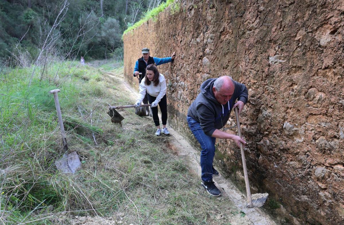Emeterio Moles, Pepita Torres y, detrás, Toni Costa, retiran fango de una acequia con la azada. | J. A. RIERA