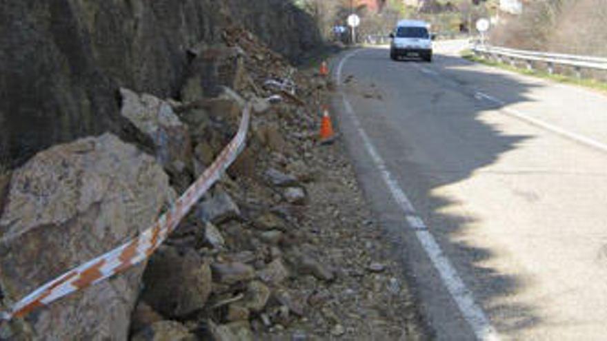 Un vehículo se dispone a invadir el carril contrario de la calzada ante el desprendimiento de piedras del talud en Arrabalde.