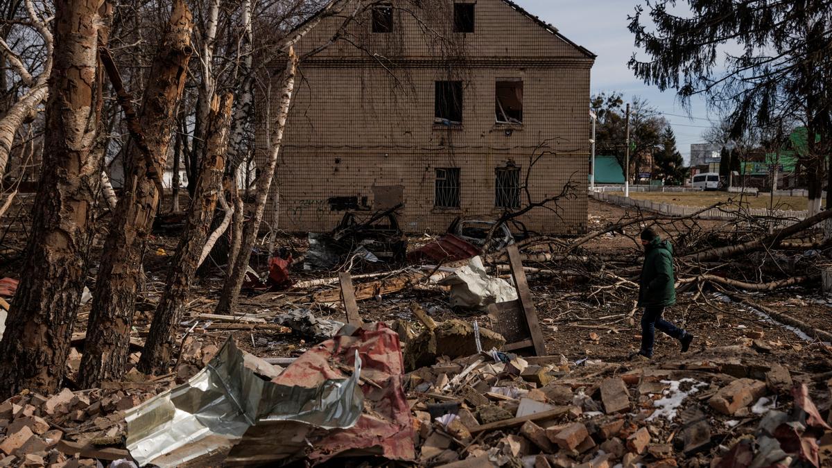 A man walks through the debris of a cultural center and an administration building that were destroyed during aerial bombing, in the village of Byshiv outside Kyiv