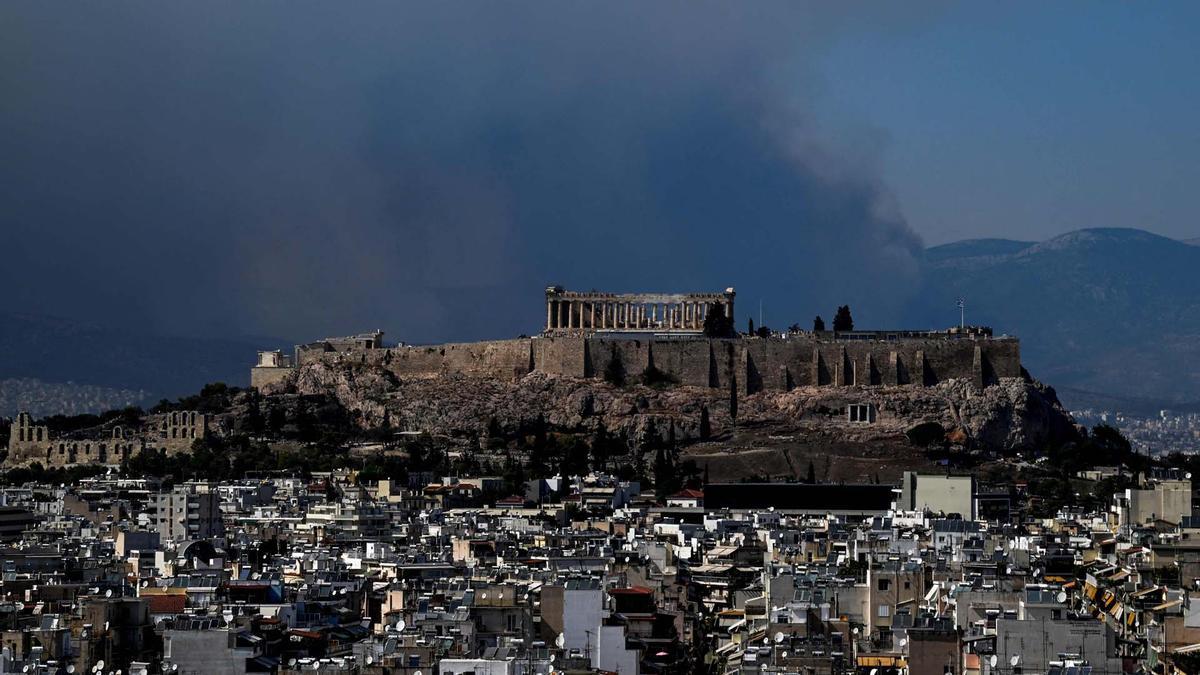  El humo se eleva detrás de la cima de la colina de la Acrópolis mientras un incendio forestal arrasa las afueras de Atenas