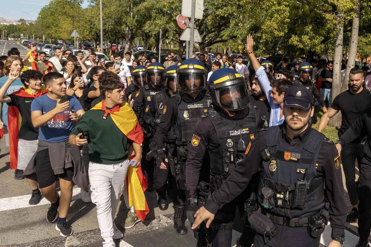 El agitador ilicitano Vito Quiles, escoltado por un cordón policial, saluda a sus seguidores instantes después de finalizar su discurso en la UA
