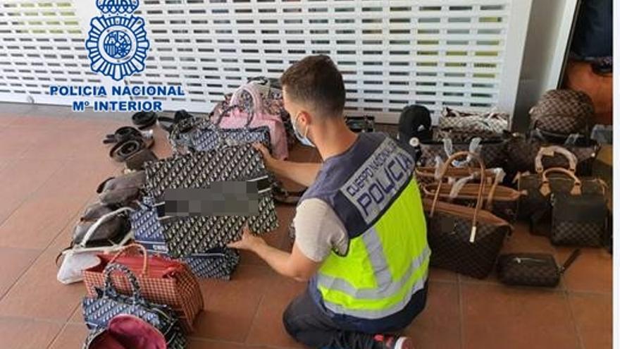 Un agente interviene algunos de los producto falsificados intervenidos en la operación policial en el sur de Tenerife