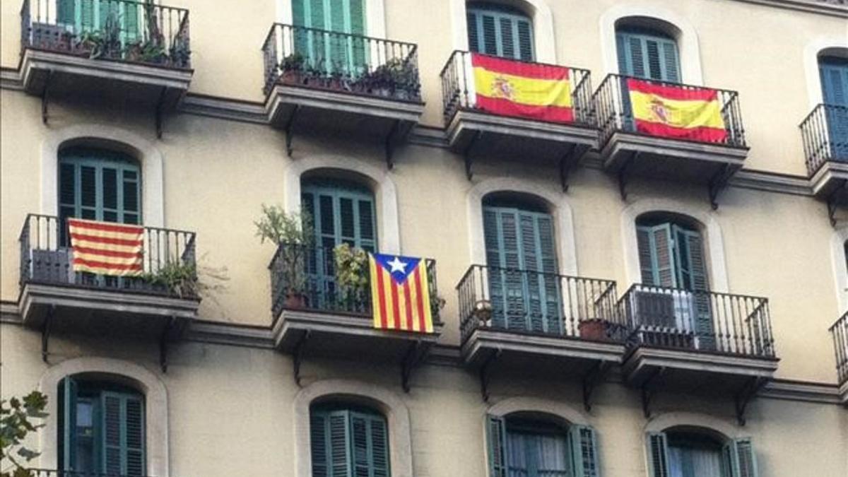 Fachada de un edificio de Barcelona con banderas española, una 'senyera' y una 'estelada'.