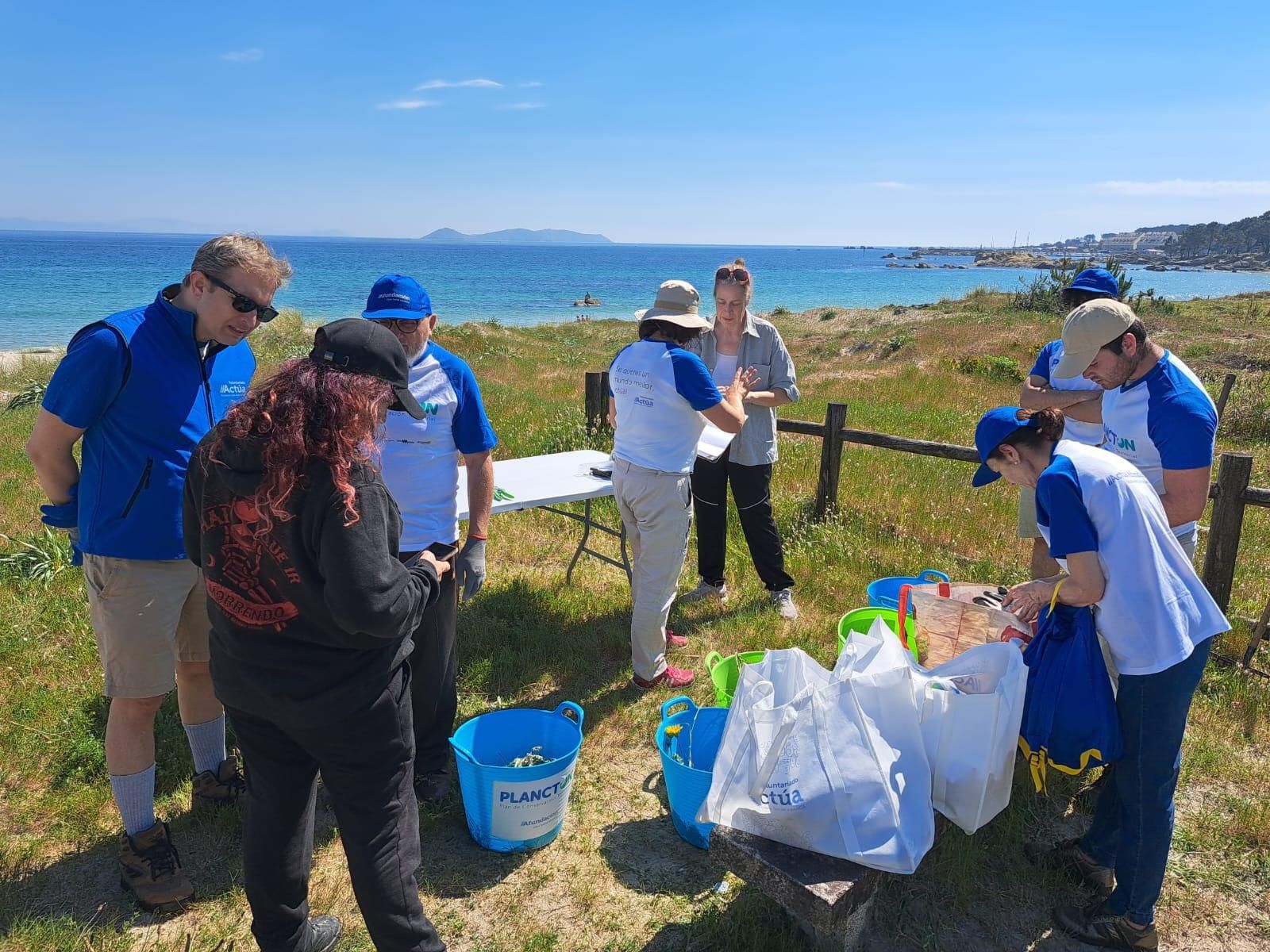 Participantes en la jornada de voluntariado que Abanca y Afundación llevan a cabo esta tarde en la playa grovense de Area da Cruz para eliminar basura marina y especies invasoras.