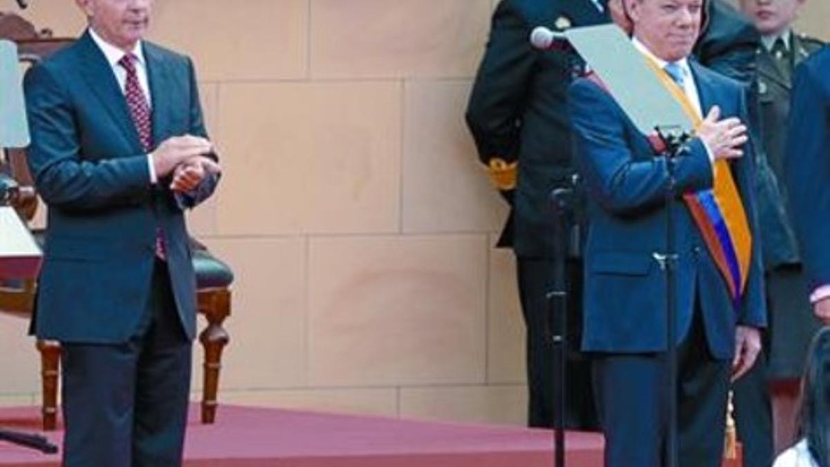 Uribe, a la izquierda, aplaude a Santos después de que anoche tomara posesión de la presidencia.