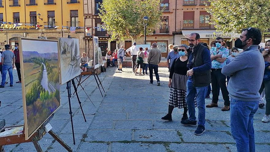 Toresanos y visitantes admiran los cuadros del certamen en La Glorieta. | M. J. C.