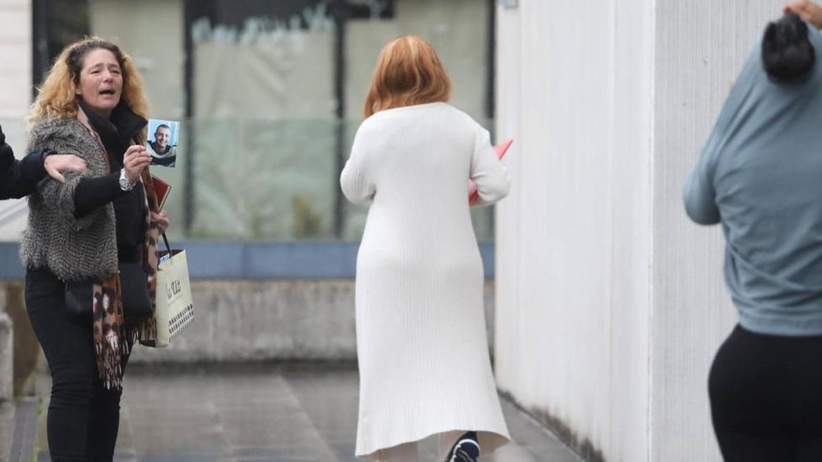 María del Carmen I. R., ayer, a las puertas del Palacio de Justicia, mostrando la fotografía de su hijo fallecido a las dos investigadas.