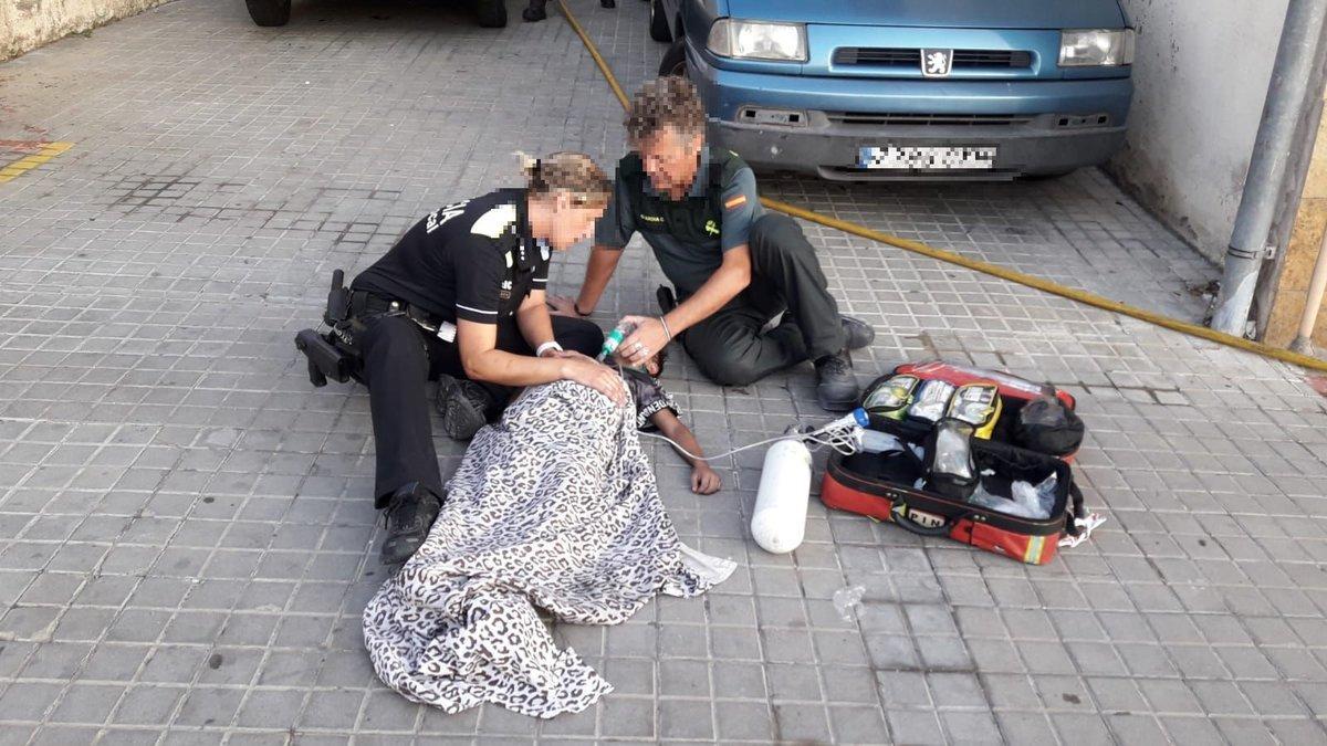 Dos agentes atienden a uno de los menores heridos durante el incendio en una vivienda de Pineda de Mar