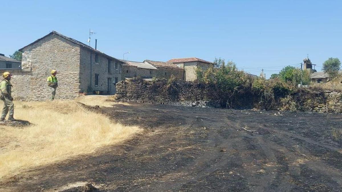 Bomberos forestales de la Junta durante las labores de extinción con el incendio ya sofocado a las puertas de las primeras viviendas en Gramedo.