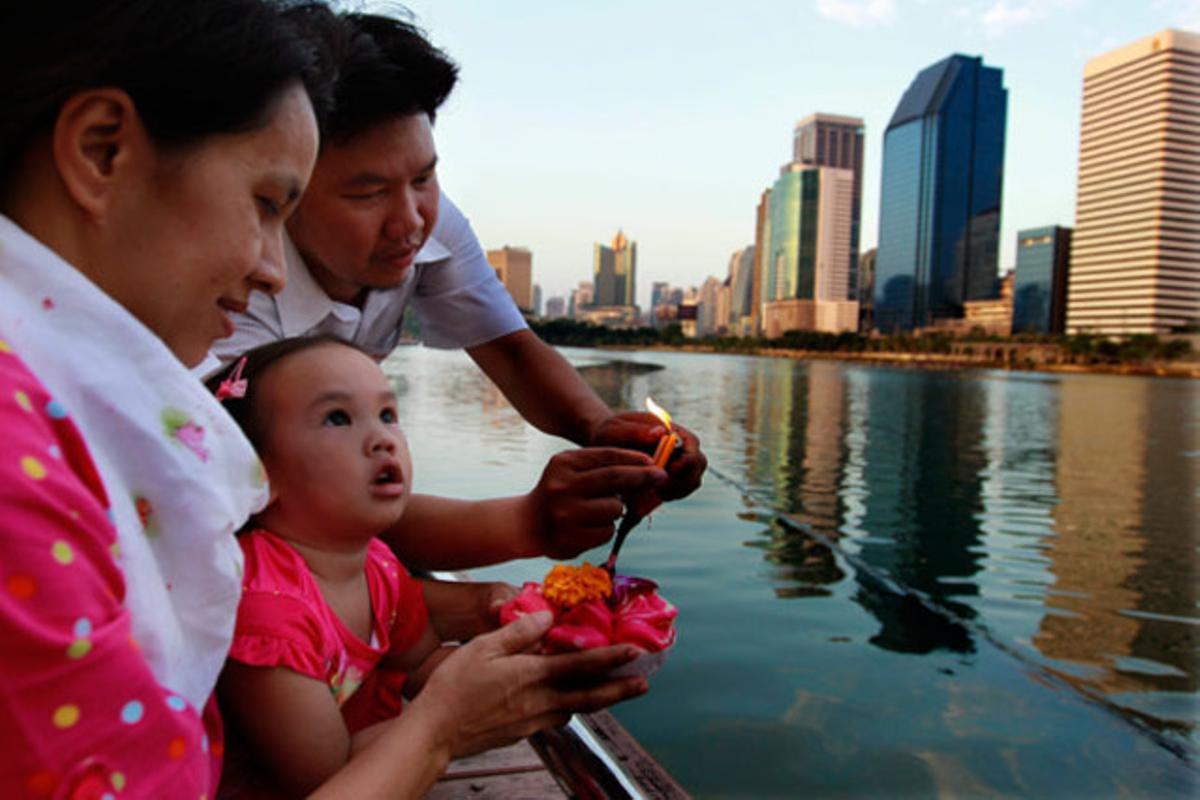 Una família encén un ’krathong’ abans de tirar-lo a l’aigua amb motiu de la celebració del festival Krathongs a Bangkok (Tailàndia).
