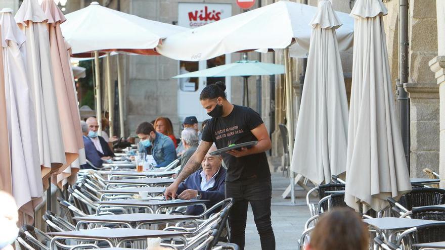 Un camarero sirve a un cliente en una terraza.