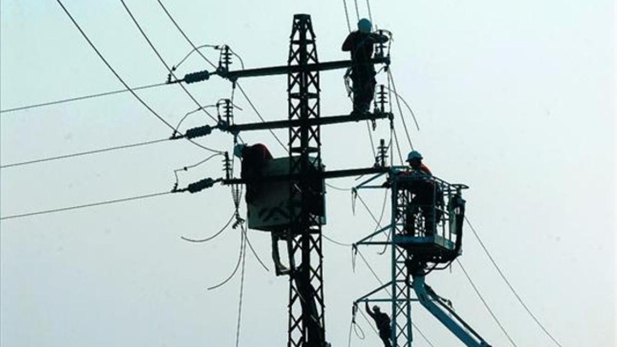 Operarios de mantenimiento en una torre de transporte de energía eléctrica, en Vallmoll (Alt Camp).