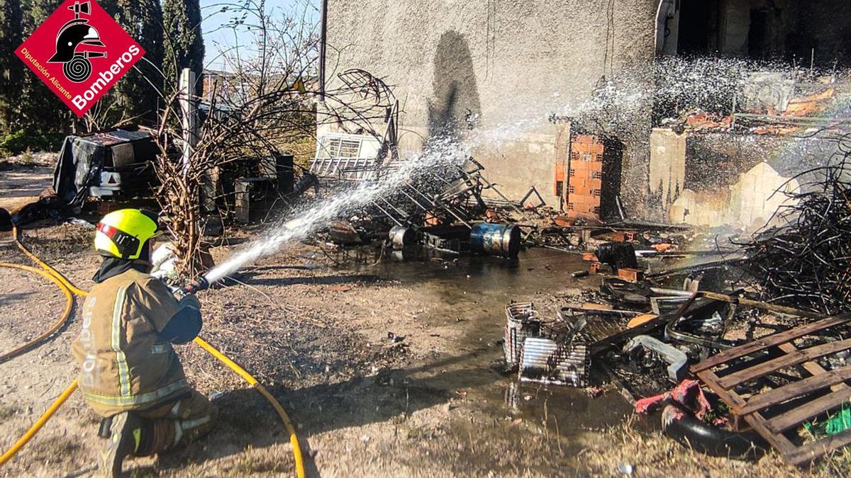 Un bombero refresca la fachada del chalet de Elche con agua.