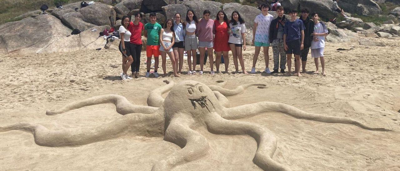 Algunos alumnos posan ante una de las figuras realizadas en la playa de A Lanzada. | // INSTITUTO MONTE DA VILA