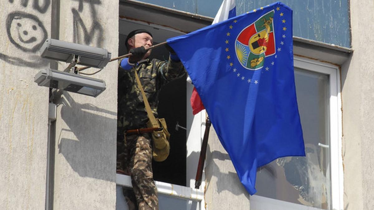 Un activista prorruso cuelga una bandera en el edificio del Servicio de Seguridad, en Lugansk.