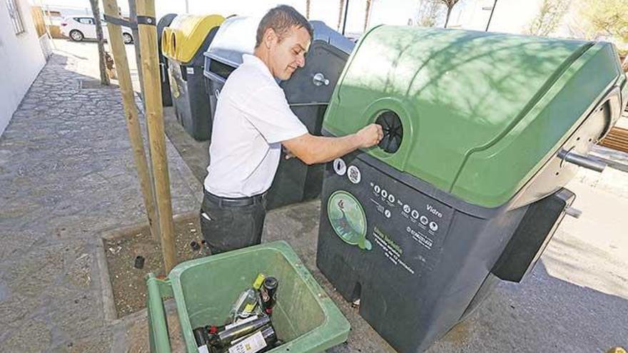 Un camarero deposita botellas en el nuevo contenedor de vidrio.