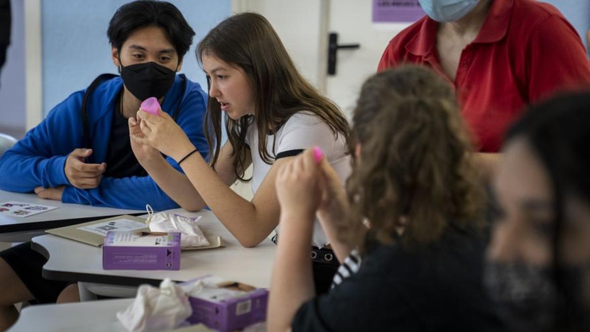 Alumnos del Institut Montjuïc examinan copas menstruales y otras alternativas sostenibles a compresas y tampones de un solo uso en el inicio del programa de educación menstrual 'La meva regla, les teves regles'.
