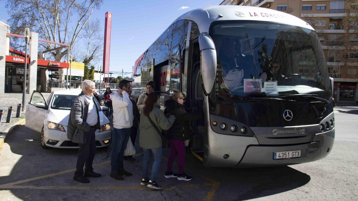 Usuarios y usuarias del servicio por carretera entre Xàtiva y Moixent suben a un autobús en la estación de ferrocarril setabense