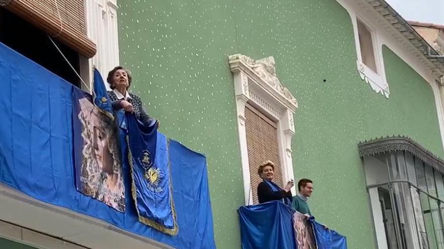 Personas en los balcones, con estandartes azules.