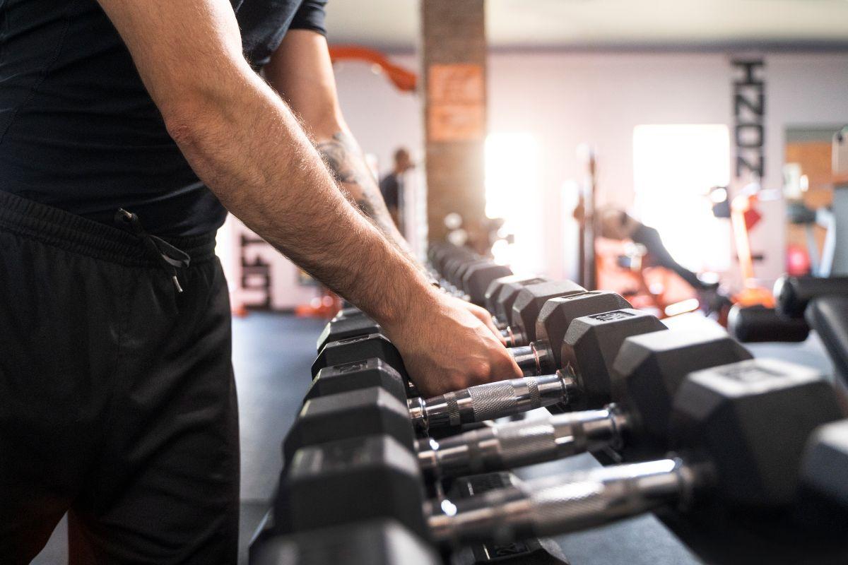 Un hombre coge una mancuerna en un gimnasio.