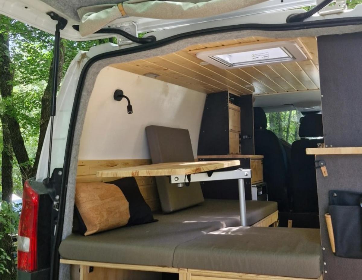 Una furgoneta aondicionada amb sofà-llit i taula