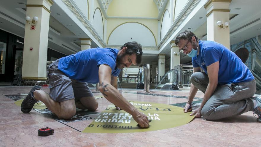 Dos operarios preparan la desescalada en un centro comercial