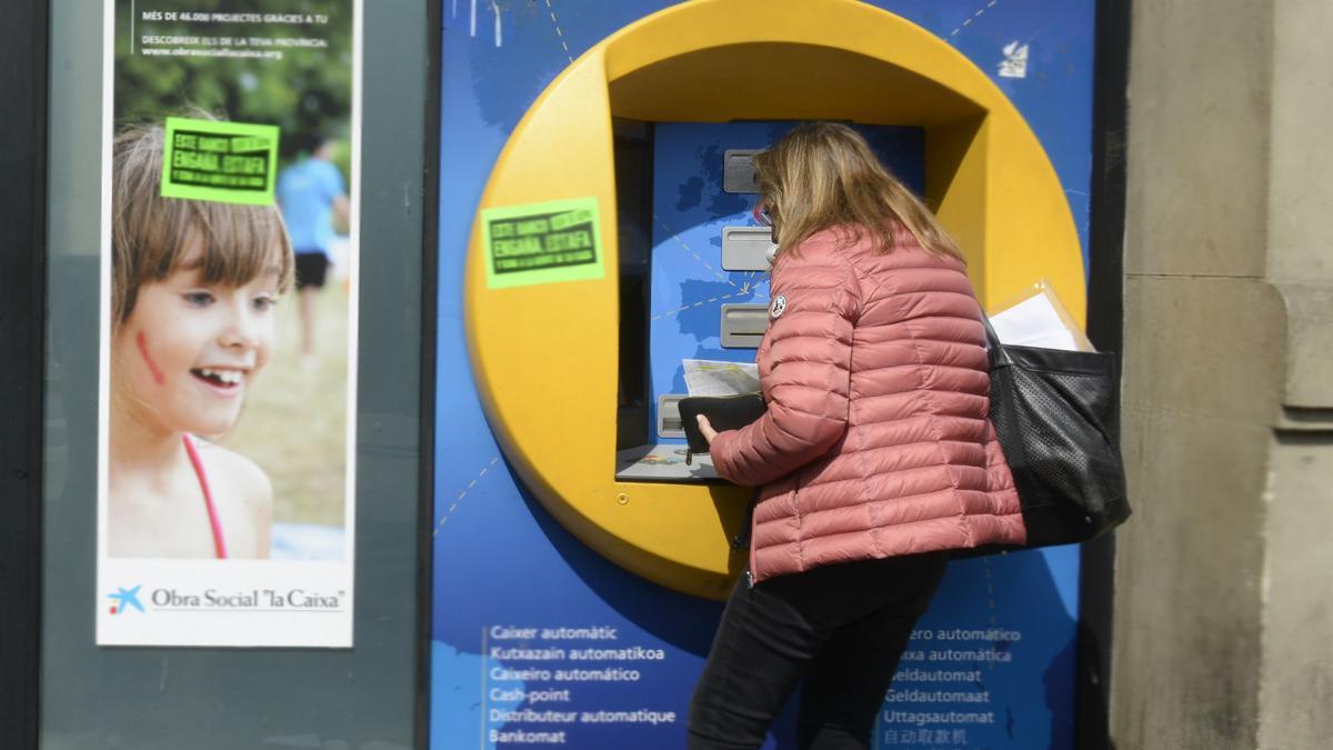 Una mujer saca dinero del cajero automático.