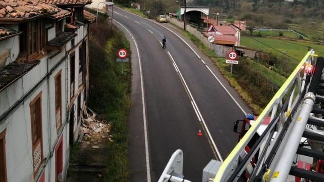 Un policía local y un camión de bomberos junto al desprendimiento.