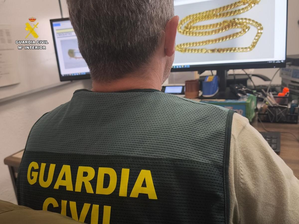 Un guardia civil examina en un ordenador una de las joyas sustraídas.
