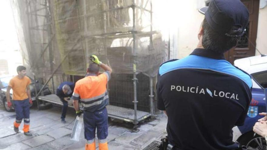 Operarios municipales examinan, ayer, el edificio número 3 de Damas, ante policías locales.