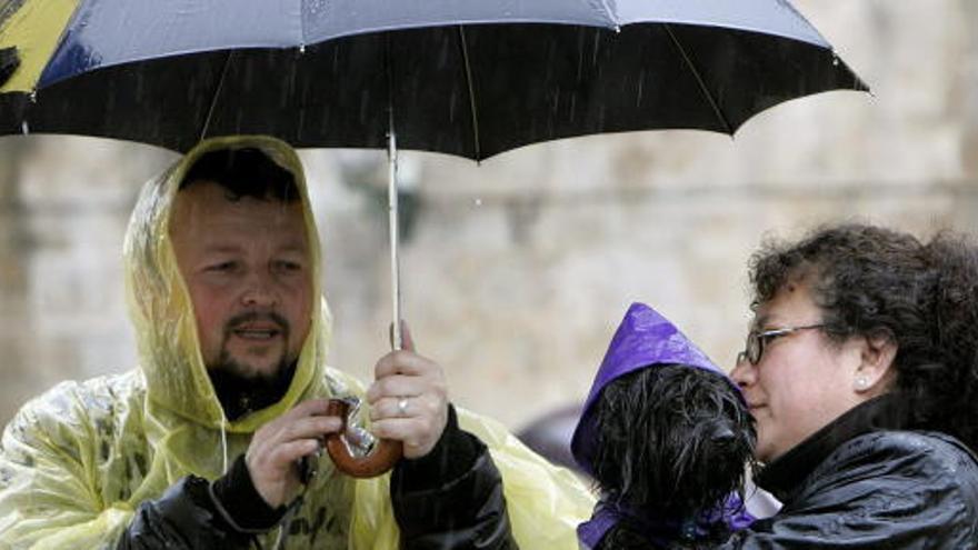 Unos turistas se fotografian bajo la lluvia.