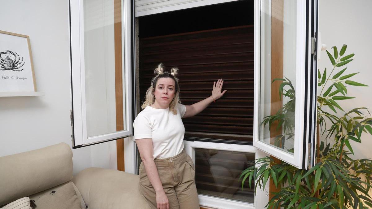 Nerea Estévez, junto a las ventanas de su vivienda selladas con barrotes.