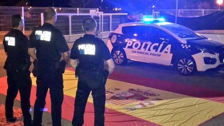 Tres agentes, frente a la bandera.