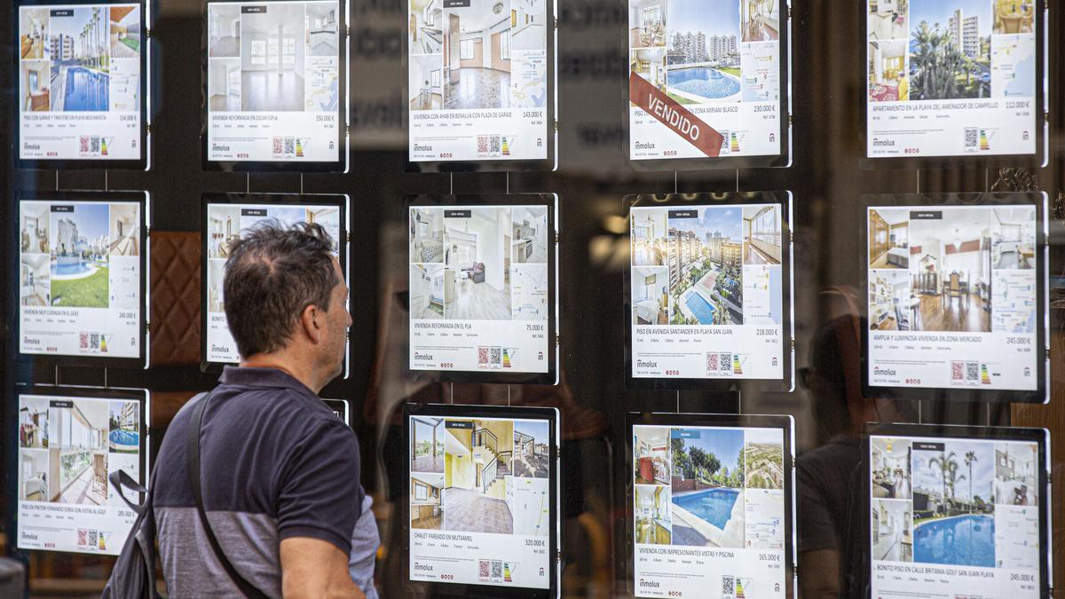 Un posible comprador mira los anuncios de una inmobiliaria en Alicante.