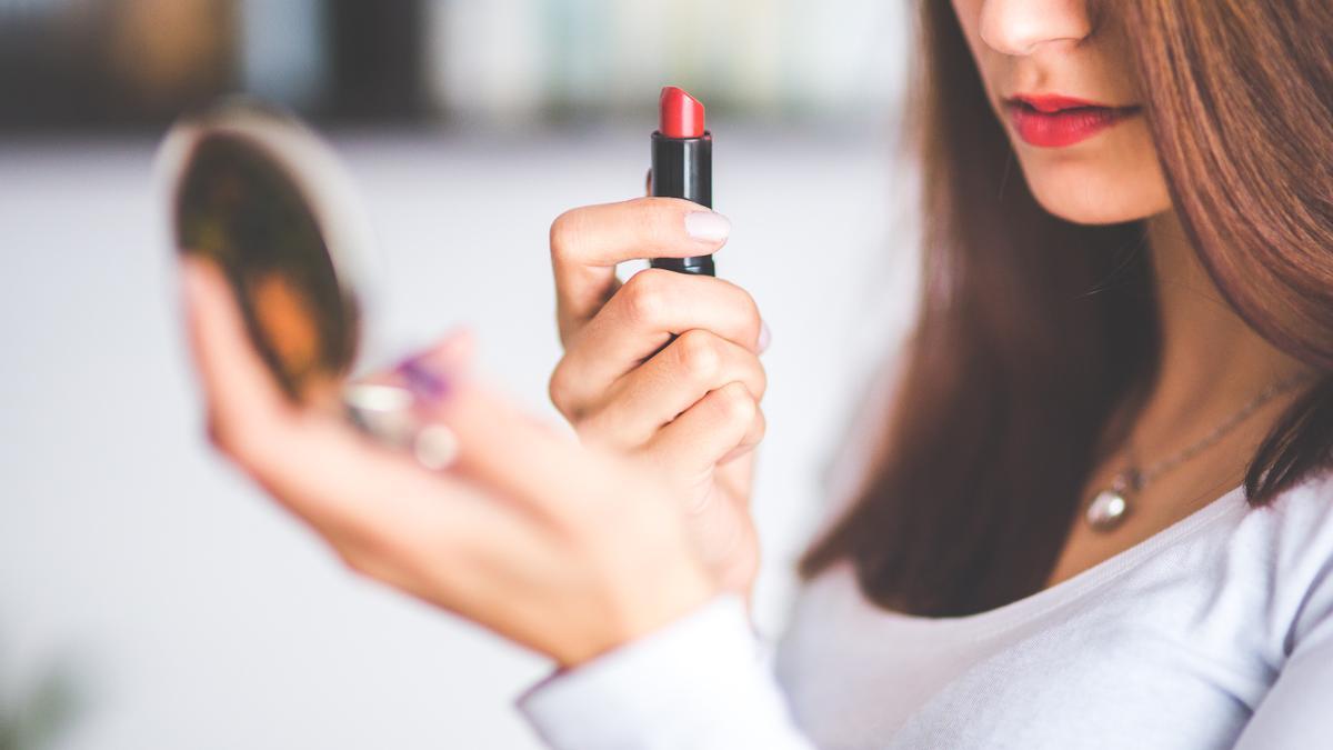 Una mujer se pinta los labios de rojo.
