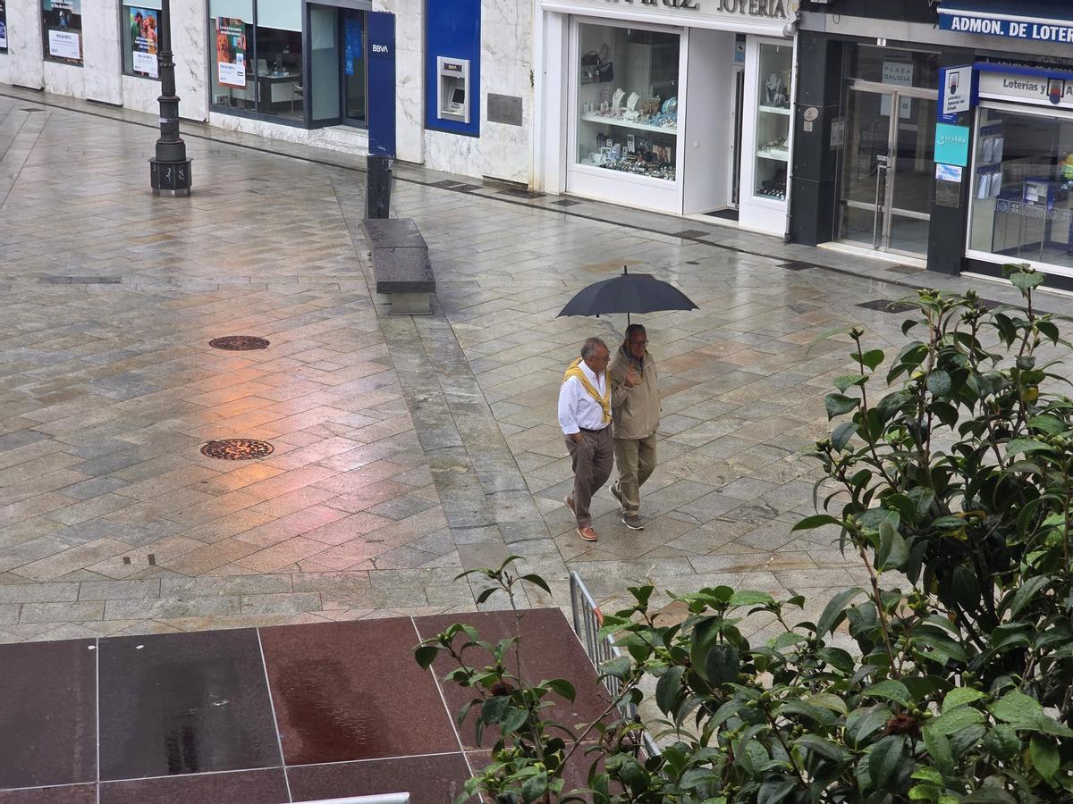 Dos hombres paseando por la vilagarciana plaza de Galicia, esta mañana.