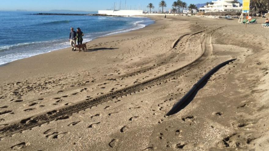 Una pareja, ayer, pasea a su perro en la playa de La Venus, descarnada y con piedras y tuberías a la vista